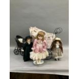 Three modern dolls with porcelain heads and jointed bodies in a Victorian style pram with lace and