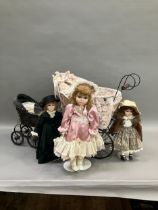 Three modern dolls with porcelain heads and jointed bodies in a Victorian style pram with lace and