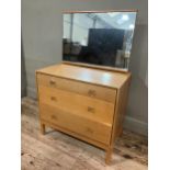 A 1960s Stag pale oak dressing chest having an adjustable mirror over three graduated drawers, on