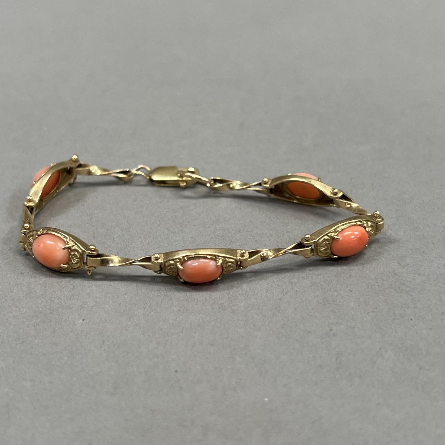 A coral bracelet in 9ct gold, each foliate patterned tonneau link claw set with an oval cabochon