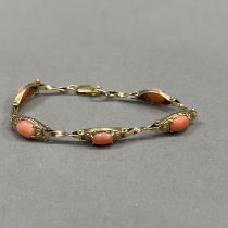 A coral bracelet in 9ct gold, each foliate patterned tonneau link claw set with an oval cabochon