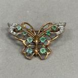 An emerald and diamond butterfly brooch in 9ct gold, claw and grain set with graduated circular