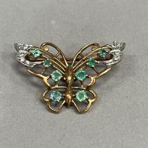 An emerald and diamond butterfly brooch in 9ct gold, claw and grain set with graduated circular