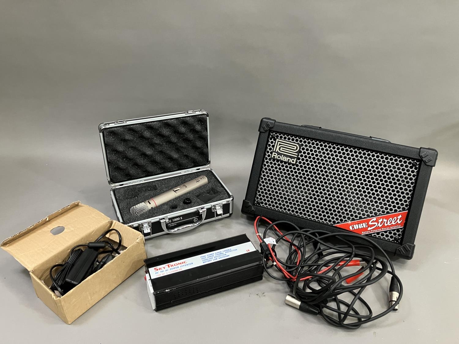 A Roland Street Cube battery powered PA amplifier, along with a cased AKG C1000S microphone and a