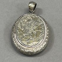A Victorian oval silver locket foliate engraved to the front with an open shield cartouche and