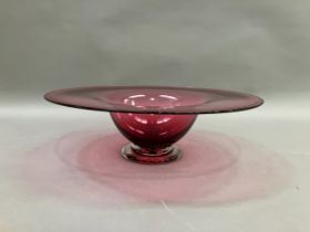 A contemporary cranberry glass bowl with broad flat and folded rim on a clear glass foot, 38cm