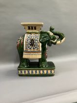 A Chinese ceramic elephant glazed in green with trunk raised and standing on a rectangular plinth,