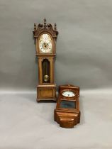 Two reproduction wall clocks, one as a long case clock