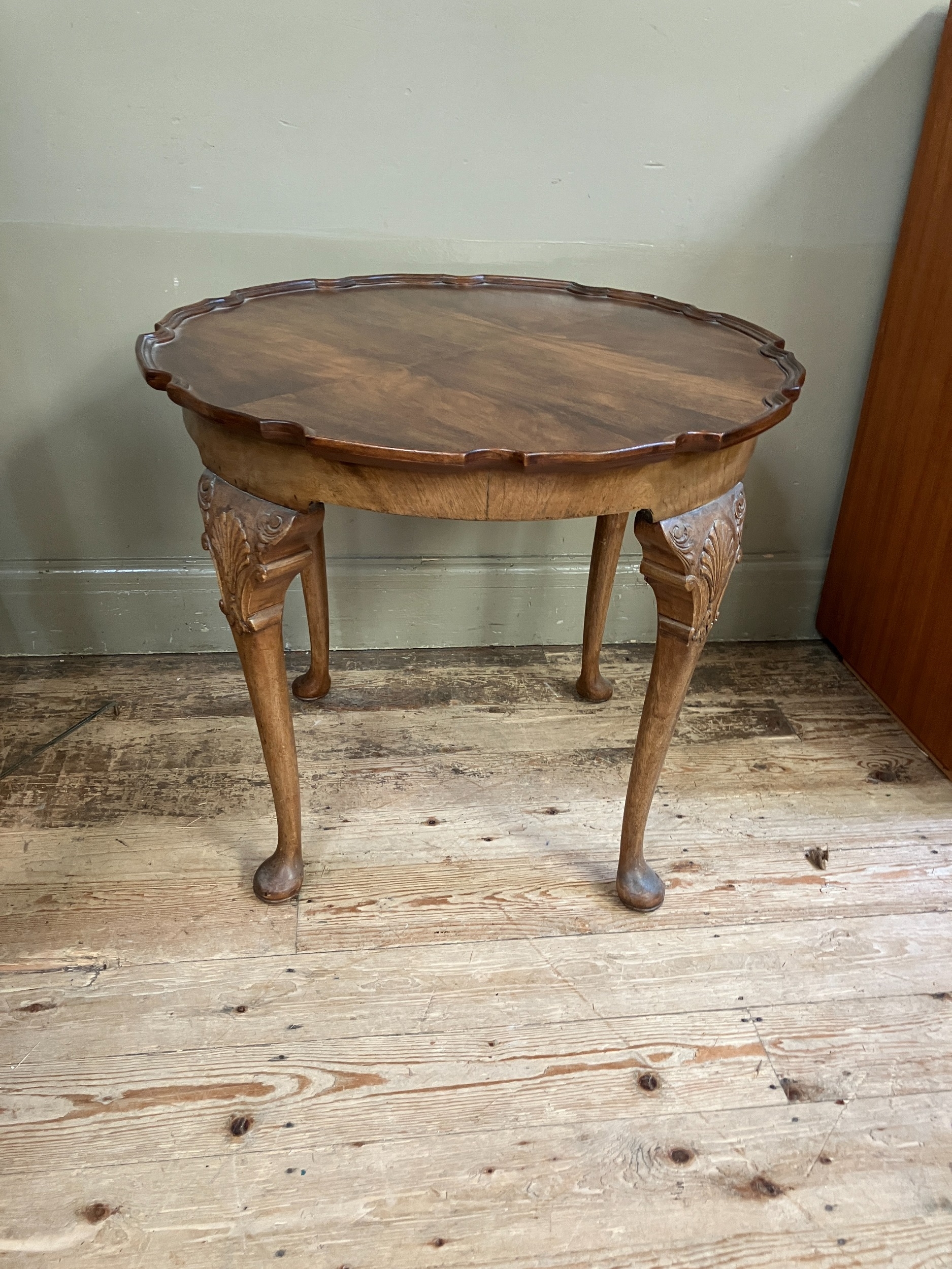A walnut quarter veneered occasional table of circular outline with pie crust rim, shell and