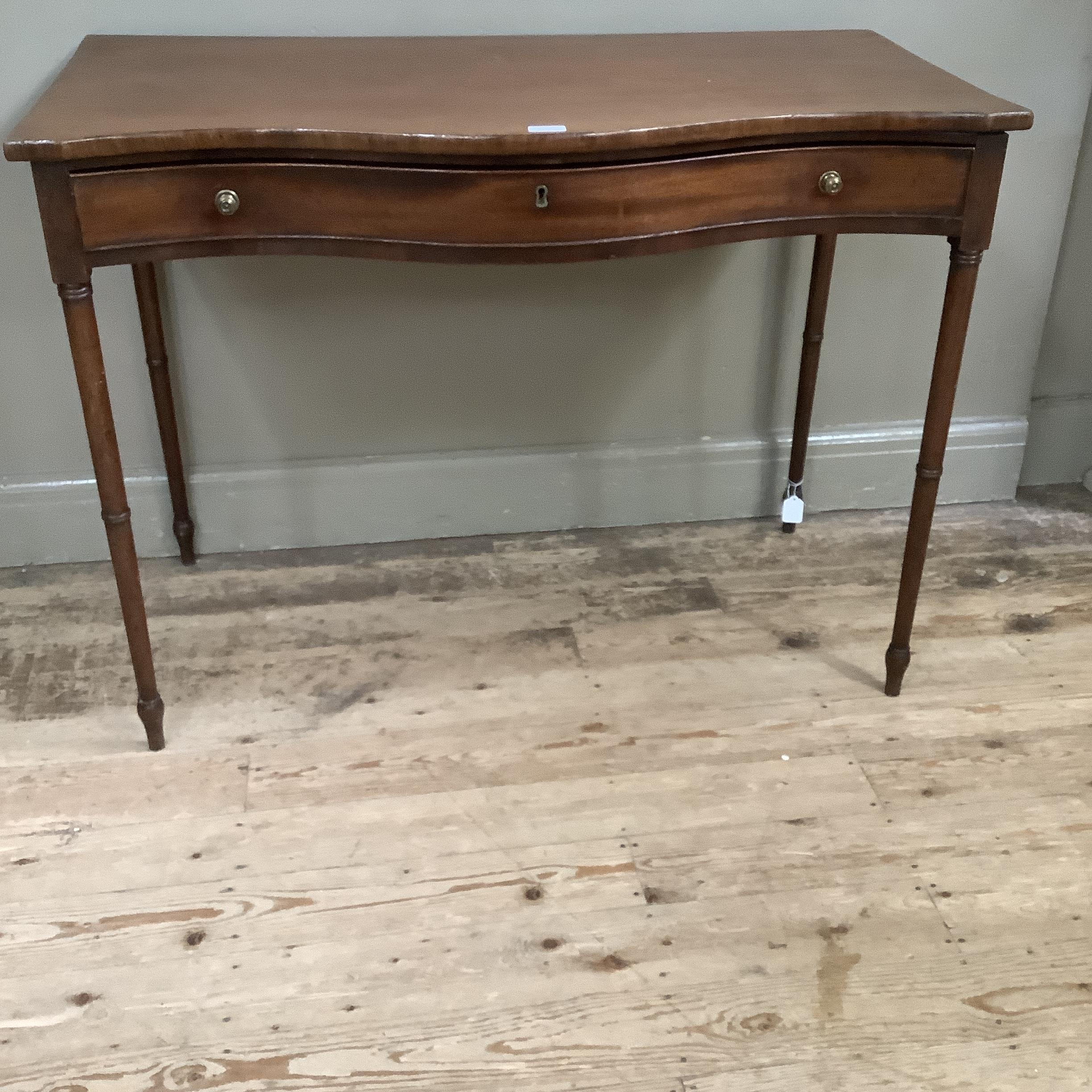 A 19th century mahogany side table of serpentine outline, having a drawer to the frieze with brass