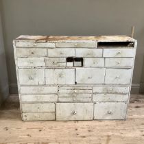 A late 19th/early 20th century set of chemist drawers in pine painted white, having numerous sized