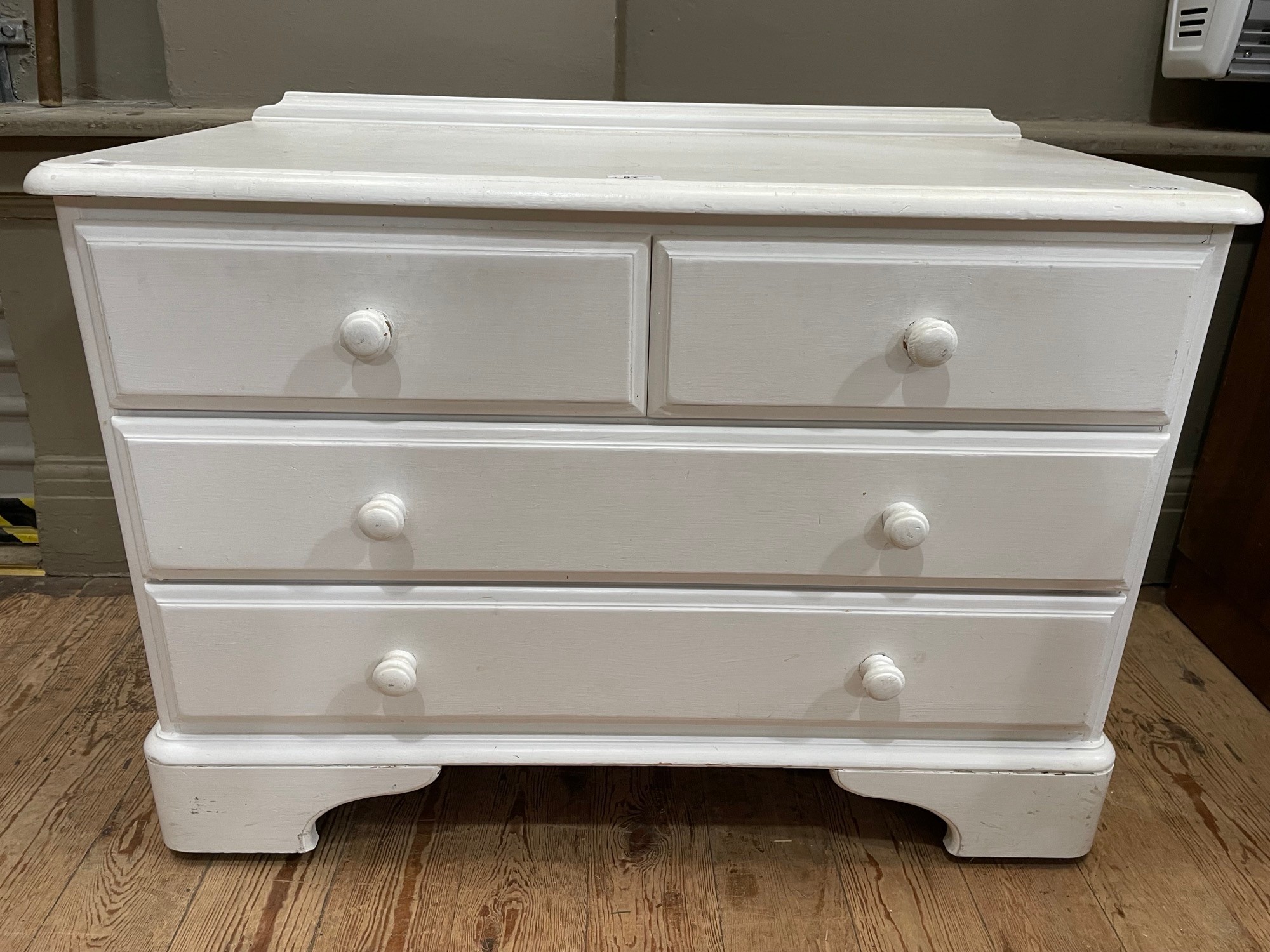 A white painted, possibly pine, chest of two short over two long drawers on bracket feet, 88cm x