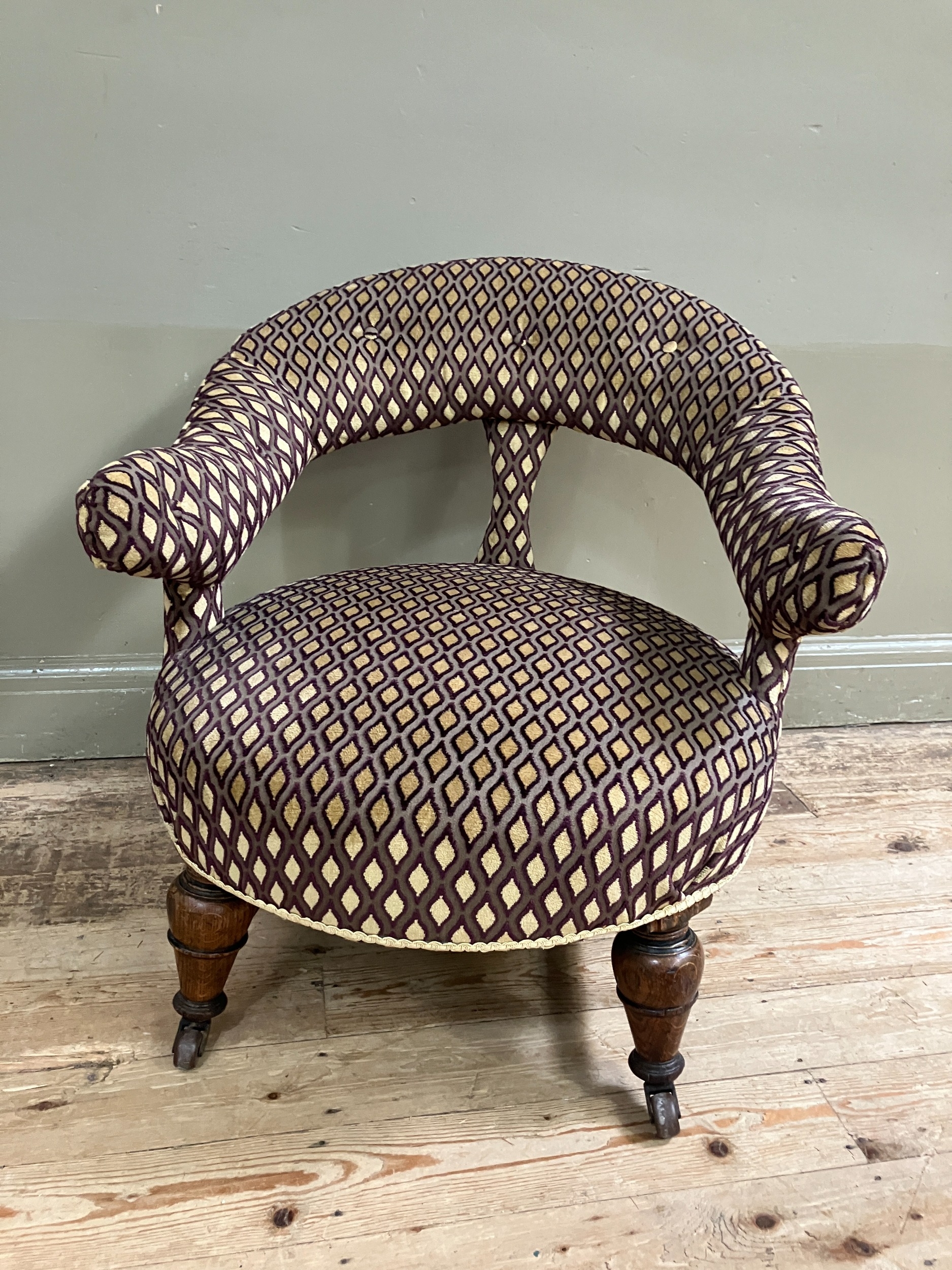 A Victorian ok armchair having an open tub shaped back, fully upholstered and on turned legs with