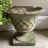 A composition garden urn with relief trellis pattern on a circular foot and square plinth, 47cm x