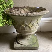 A composition garden urn with relief trellis pattern on a circular foot and square plinth, 47cm x