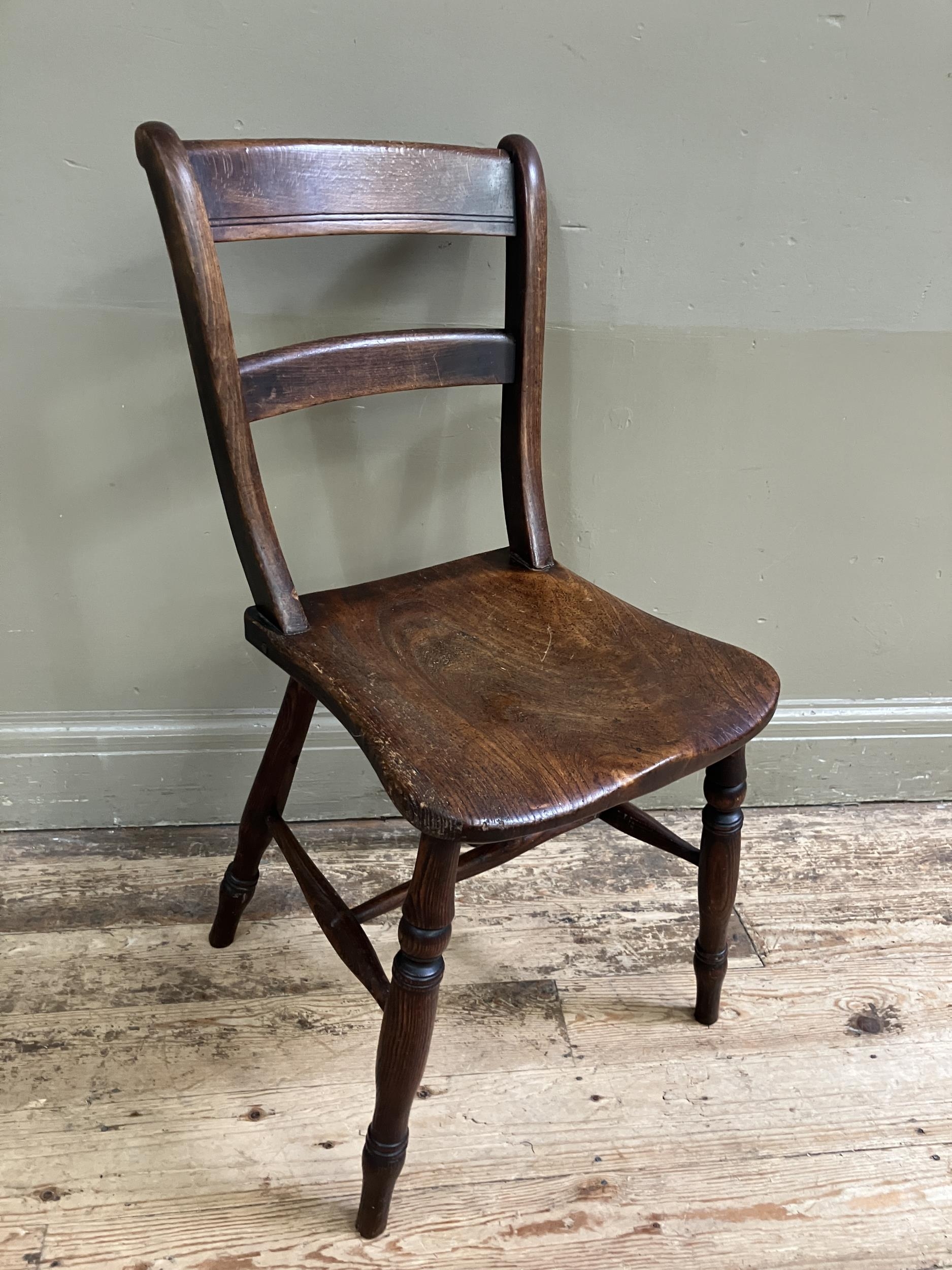 A late 19th/early 20th century fruitwood kitchen chair with bar back and tie rail, saddle shaped