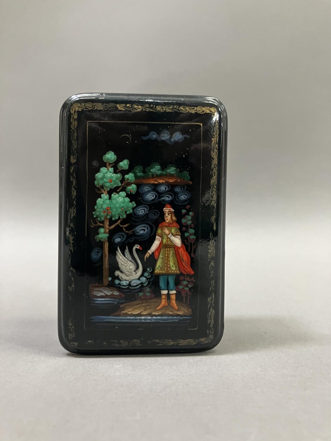 A Russian black lacquered trinket box, rectangular, the cover painted with a figure and swan, 8.