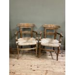 A pair of 19th century continental fruitwood kitchen armchairs having a shaped top rail and tie