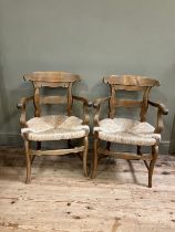 A pair of 19th century continental fruitwood kitchen armchairs having a shaped top rail and tie