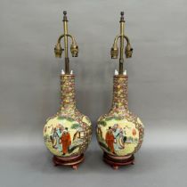 A pair of Chinese vase shaped table lamps painted with dignitaries in a garden landscape against a
