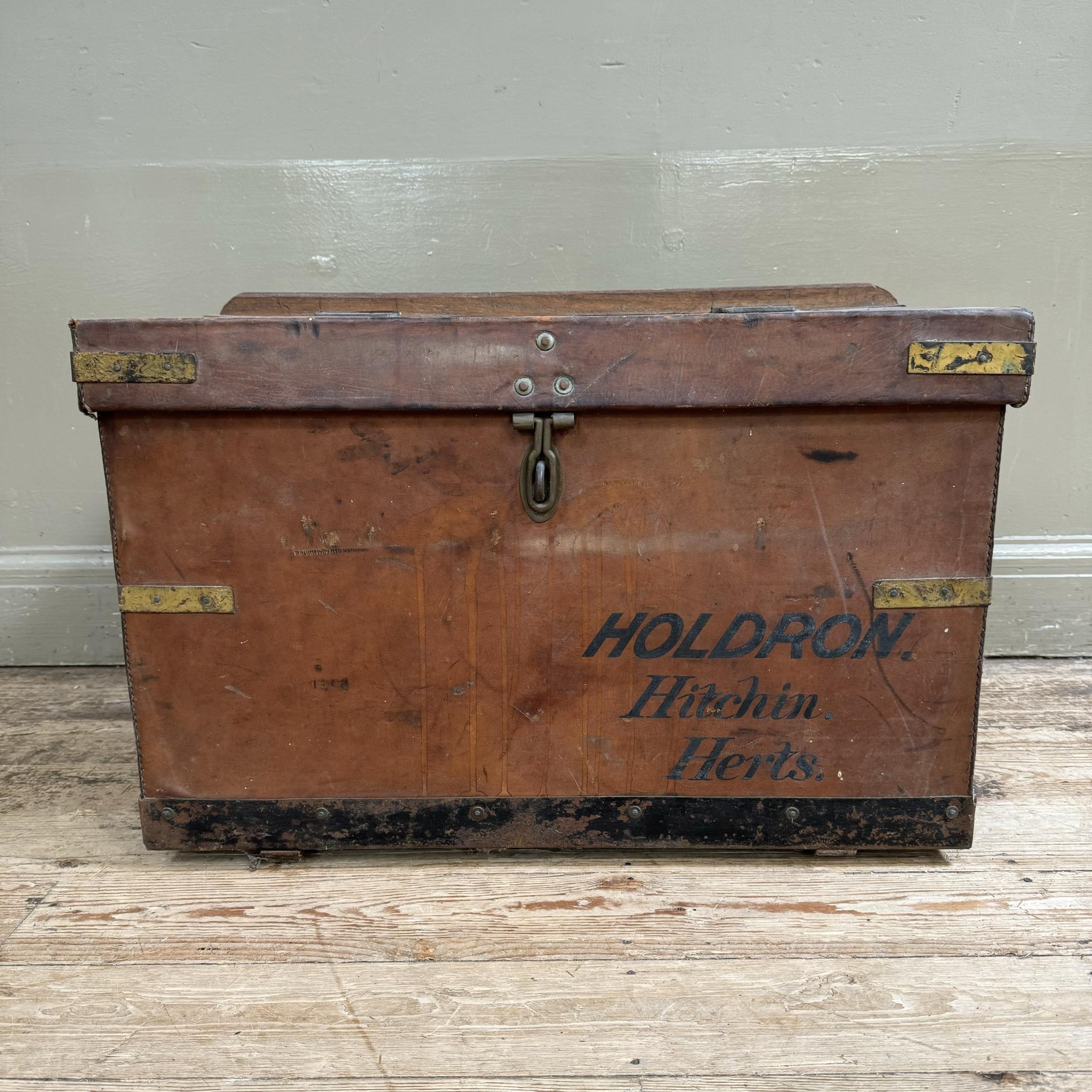 An early 20th century leather trunk with brass strapwork with metal strap holders to the rear