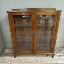 A mahogany and glazed book case cupboard with a short raised back and on short cabriole legs,