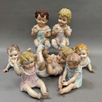 A group of seven reproduction Bisque piano babies, 25cm to 16cm