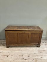 An oak blanket box having a triple indented panel top and conforming front on style feet, 108cm x