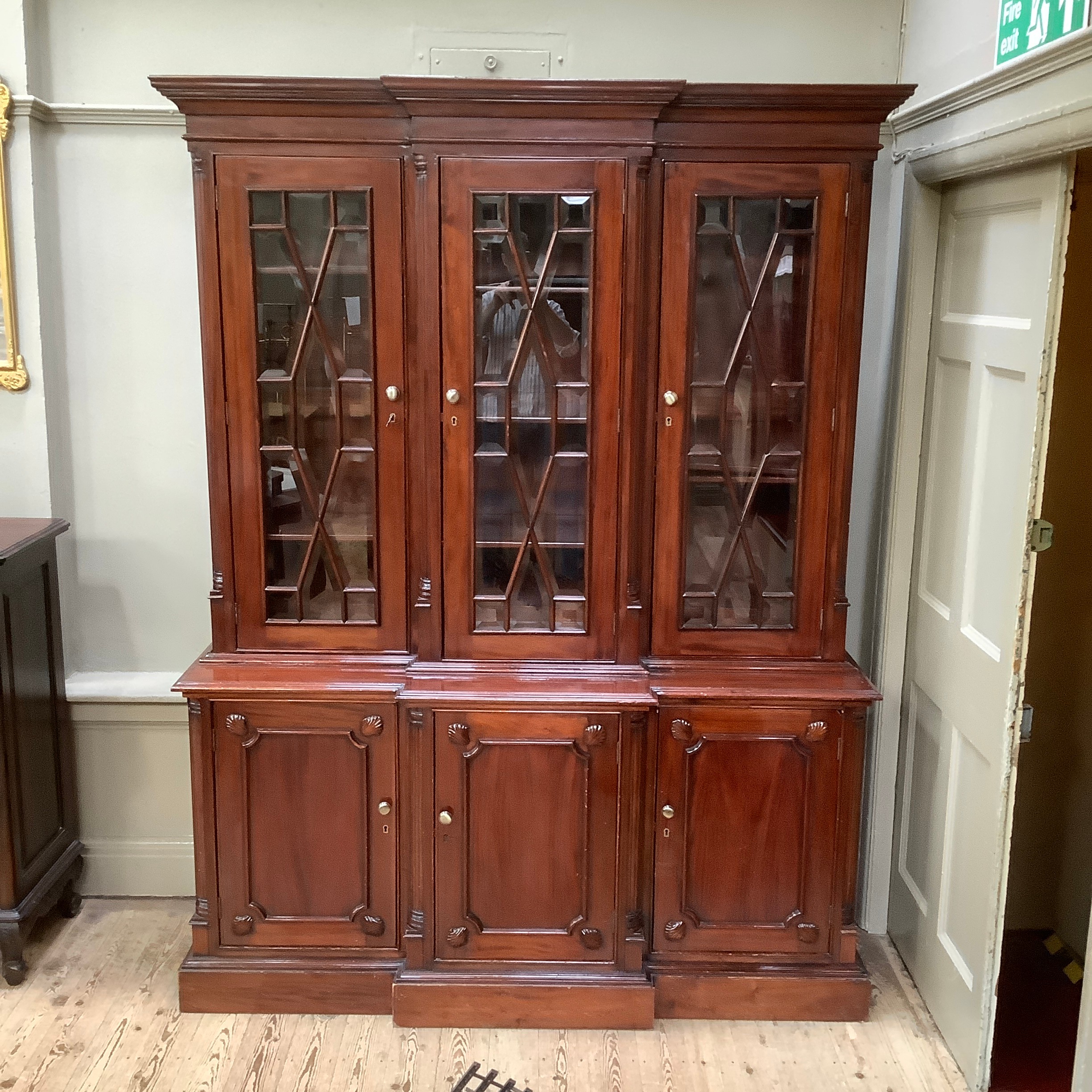 A reproduction 19th century style mahogany breakfront bookcase cupboard having a moulded cornice