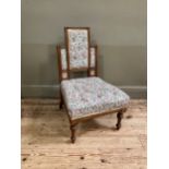 A late 19th century aesthetic walnut nursing chair having a rectangular stepped back inset with
