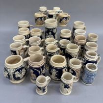 A large quantity of German pottery steins glazed in blue and with relief moulded scenes