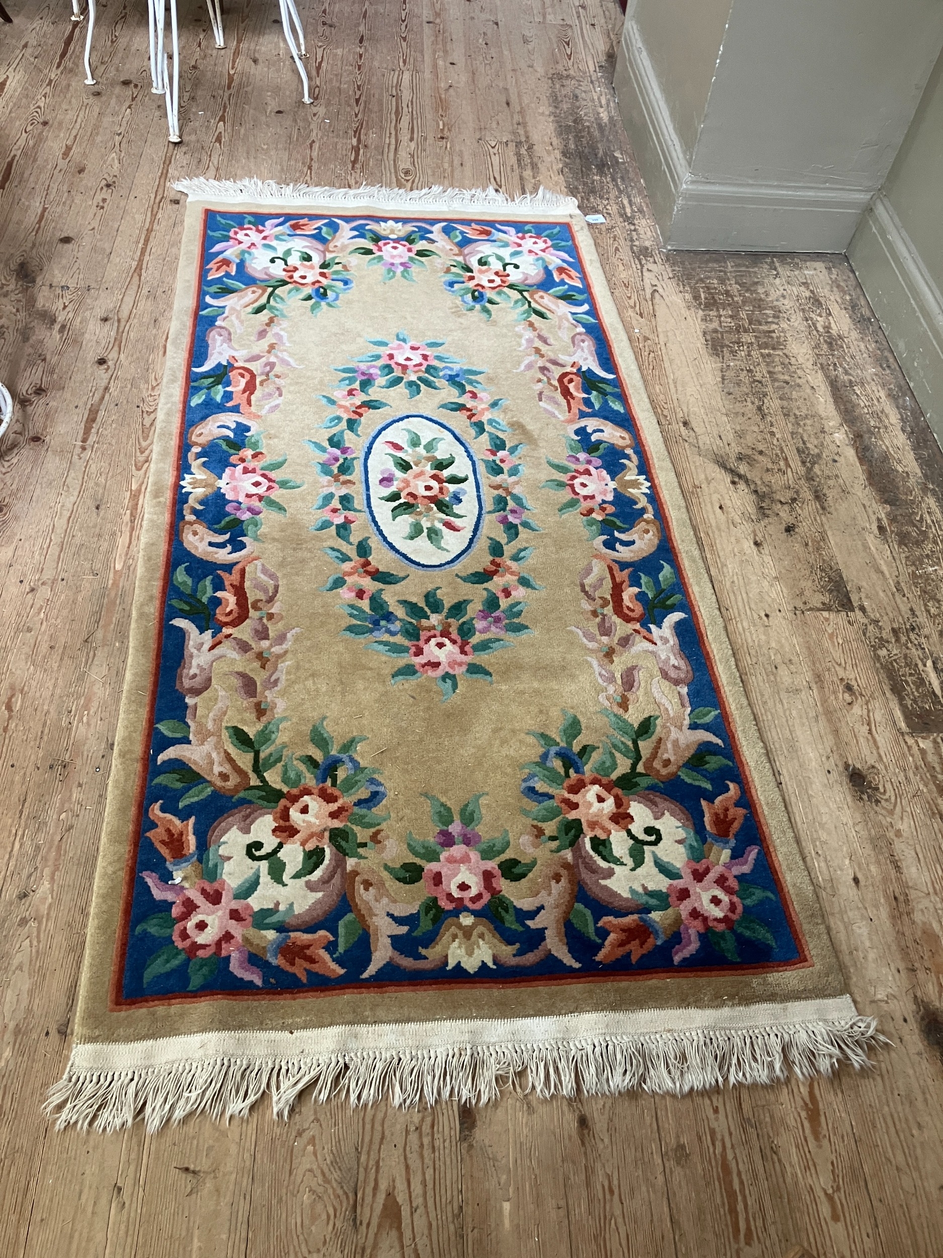A Chinese wool rug of blue, rose, green, ivory and camel in a floral design