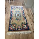 A Chinese wool rug of blue, rose, green, ivory and camel in a floral design