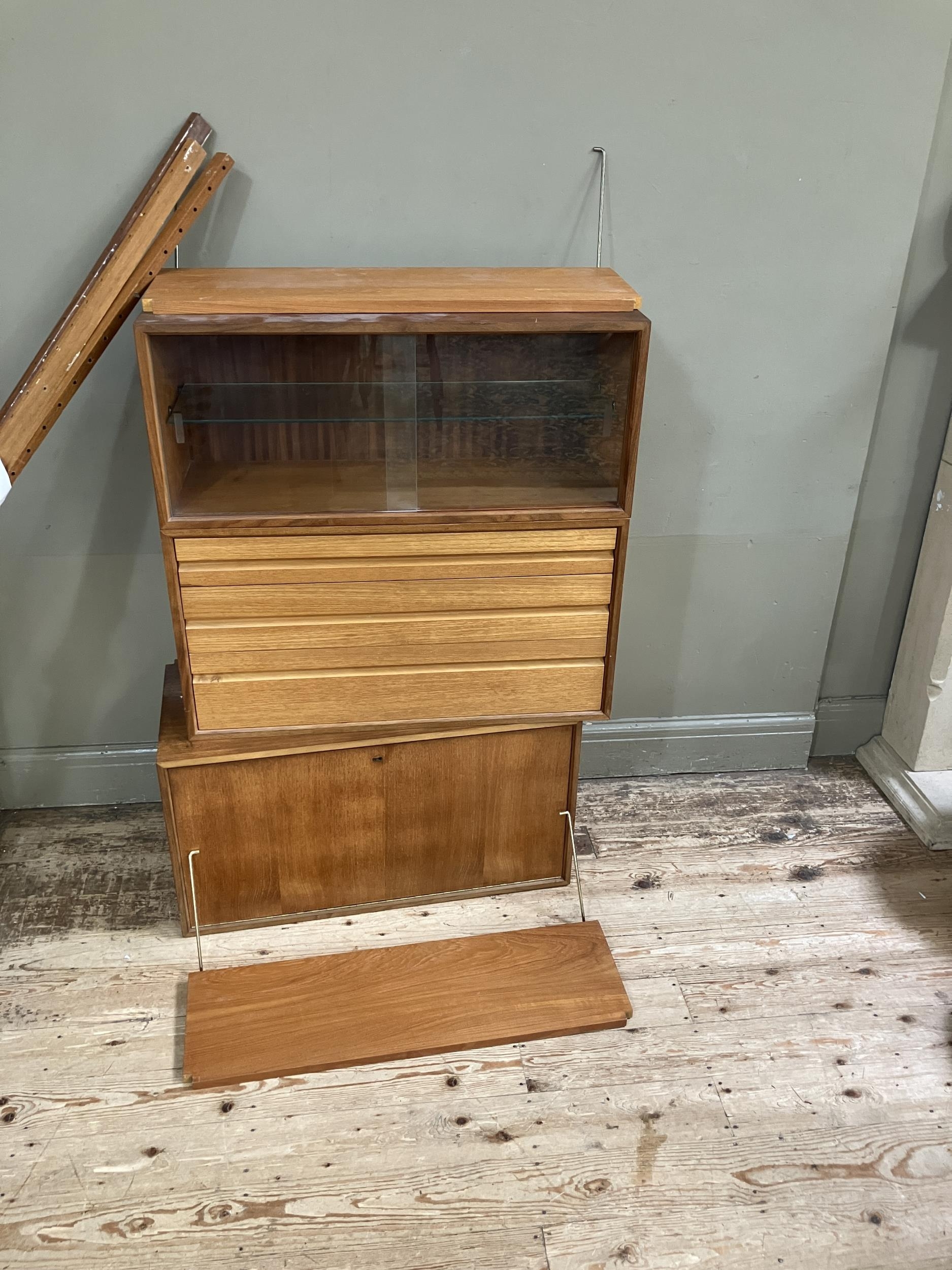 A 1970s style wall hanging unit comprising two shelves, a cupboard unit with sliding glass doors,