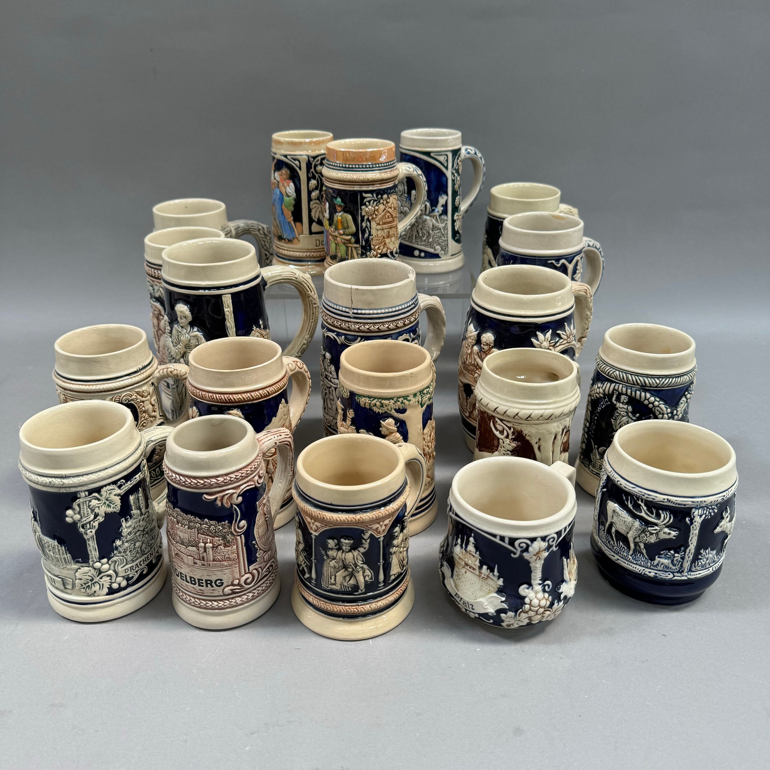 A large quantity of German pottery steins glazed in blue and with relief moulded scenes