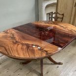 A figured mahogany quarter veneered circular extending dining table on a tripod base with reeded