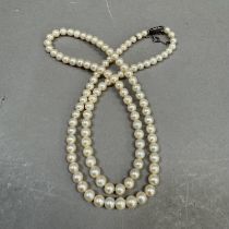 A cultured pearl necklace, the approximate 6mm pearls fastened with a lozenge shaped engraved silver