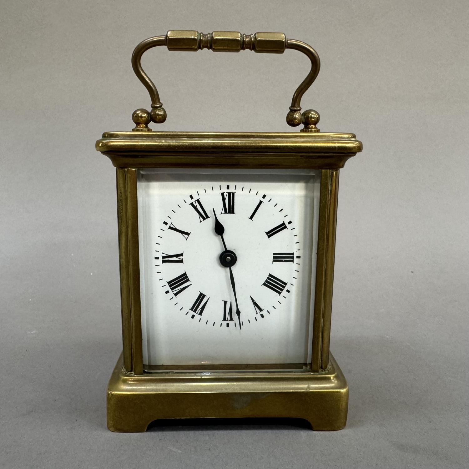 An early 20th century brass carriage clock, enamel dial with black Roman numerals, 13cm over handle