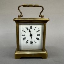 An early 20th century brass carriage clock, enamel dial with black Roman numerals, 13cm over handle