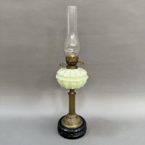 A Victorian pale green moulded glass and brass oil lamp on black circular base