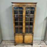 A mid 20th century walnut and glazed bookcase cupboard, having a moulded cornice above two tracery