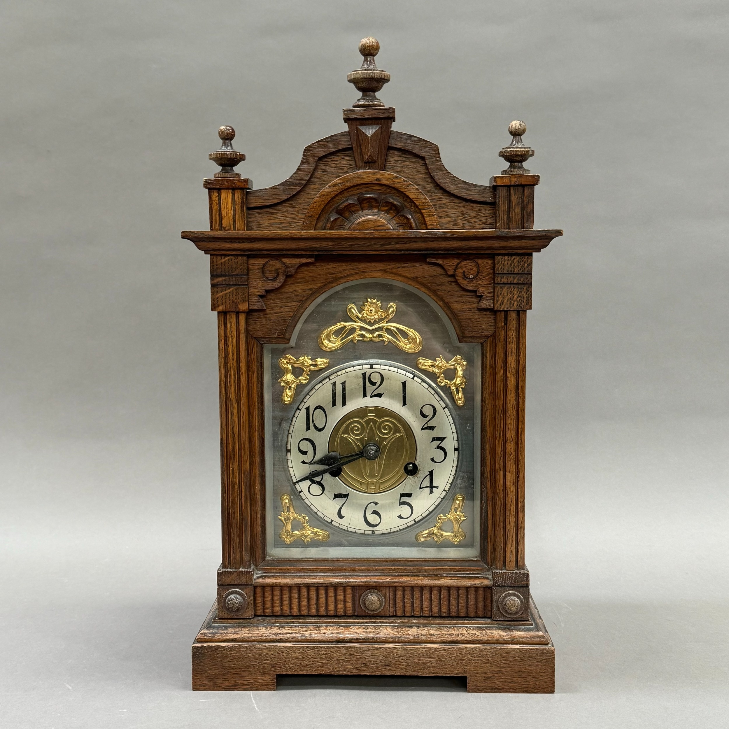 A late 19th century oak mantel clock having a silver chaptering with black Roman numerals, applied