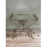 A gilt metal mirror topped tray table on cross legs, 69cm x 38cm