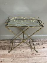 A gilt metal mirror topped tray table on cross legs, 69cm x 38cm