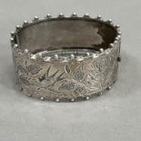 A Victorian silver stiff hinged bangle, engraved to the front with flora and fauna within beaded and