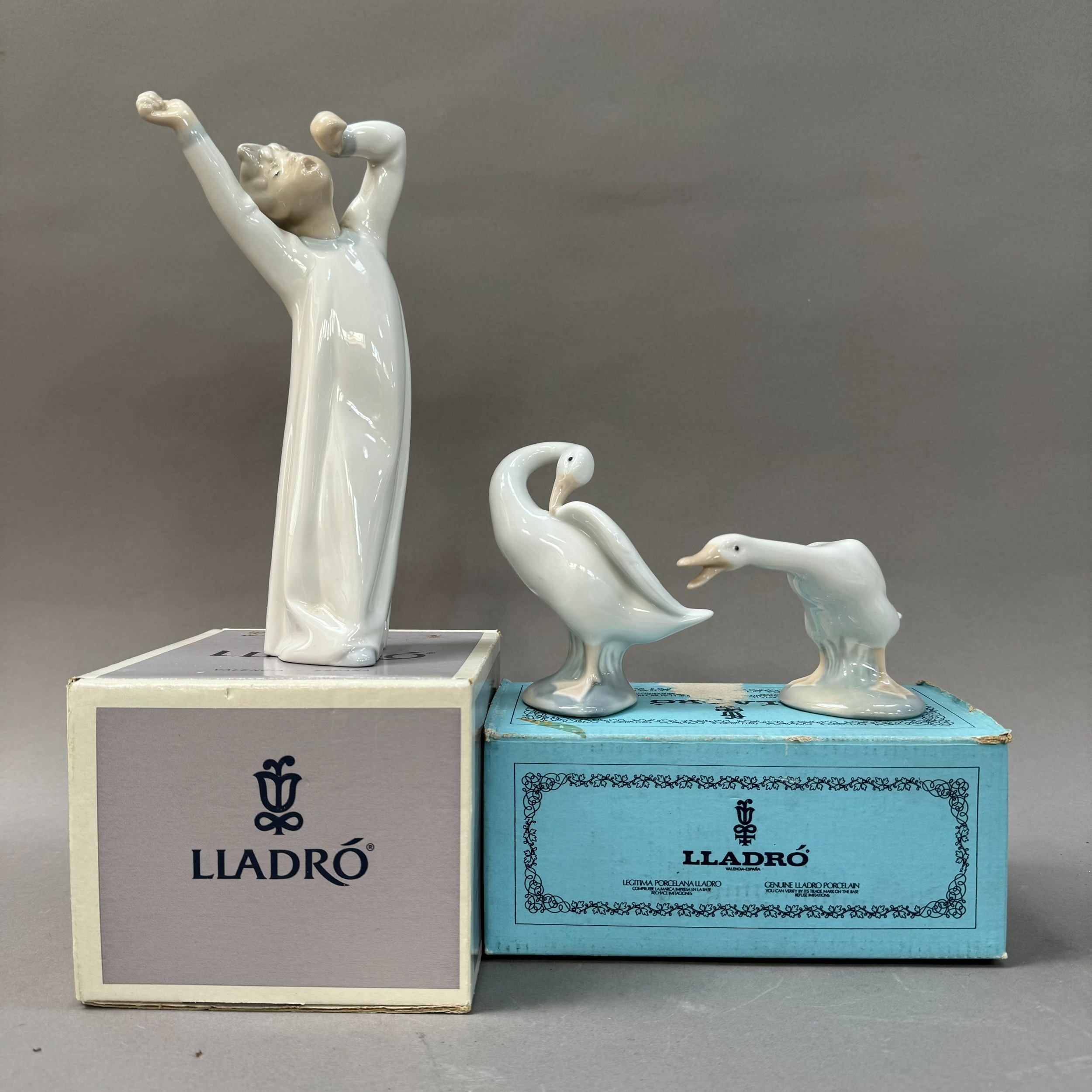 A Lladro figure of a boy in nightgown yawning together with a goose, boxed and a third goose unboxed