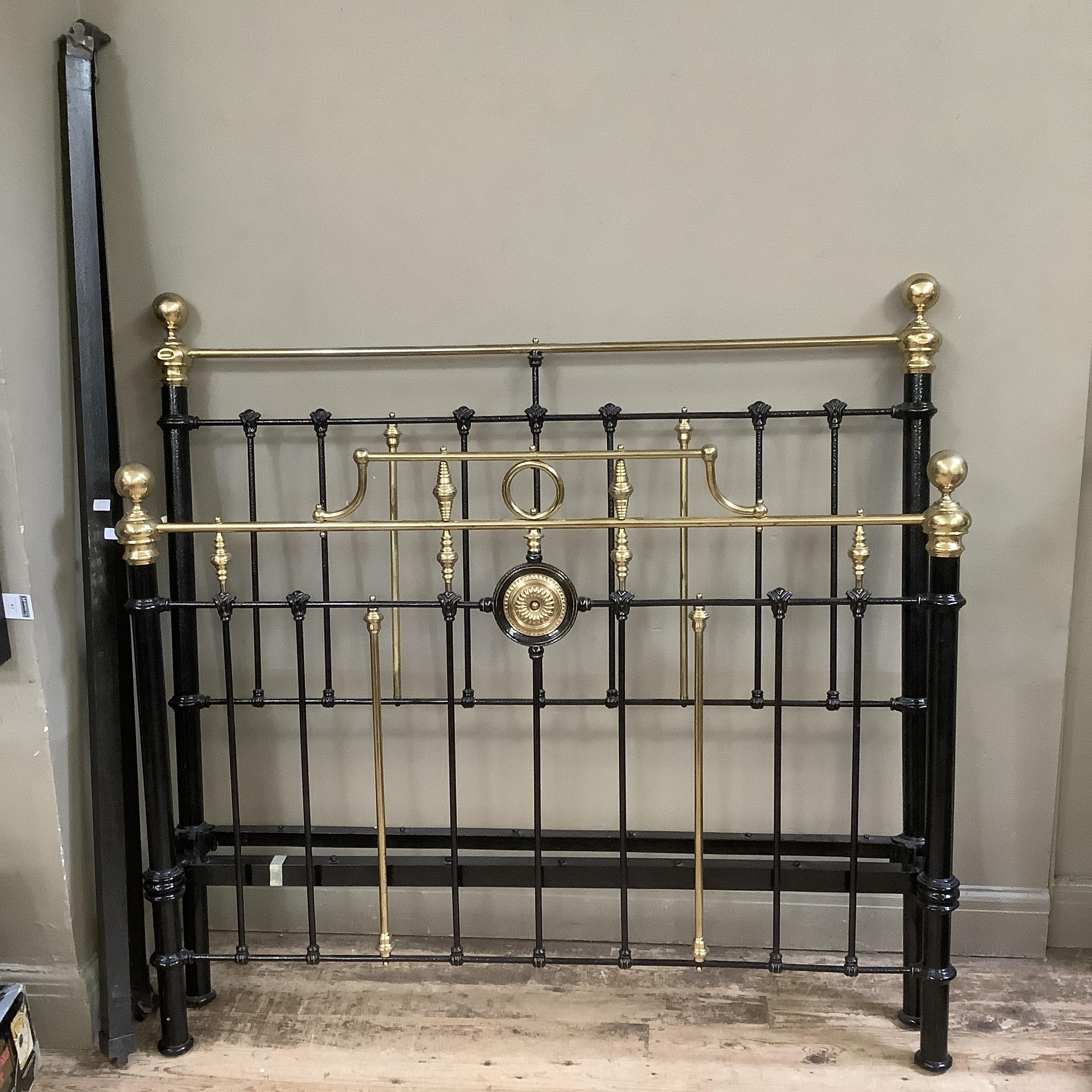 A Victorian brass and iron double bedstead with gallery rail and measuring approximately 5 feet by 6