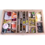 An assortment of fly tying materials including silks, feathers, wool, packets of dyed materials, a
