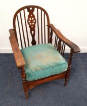 1930's OAK WHEELBACK ARMCHAIR with a folding arch back above shaped arms and a loose seat cushion,