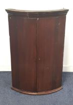 GEORGE III MAHOGANY BOW FRONT CORNER CUPBOARD with a pair of doors opening to reveal a shelved